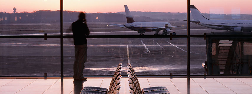 Man talking on mobile phone looking at airplane in airport