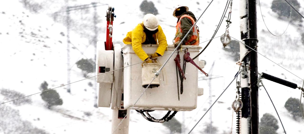 Two workers in bucket truck doing construction work on power lines.